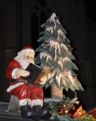 Lesender Weihnachtsmann vor Tannenbaum