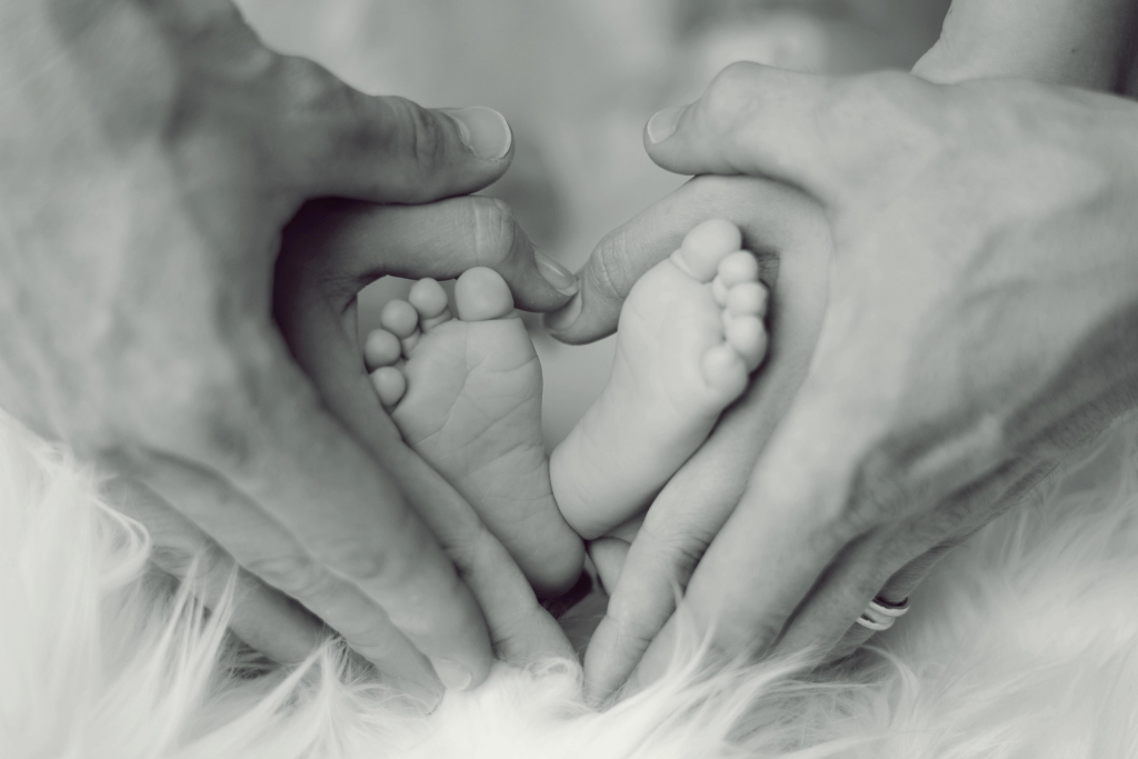 Hände der Eltern umfassen Füße des Babys
